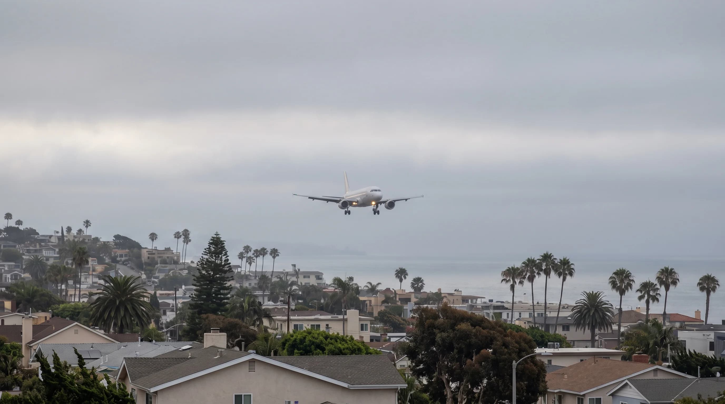 An airliner descending through a low gray cloud ceiling on final approach